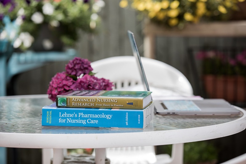 Two nursing textbooks sit on an outside table, with a laptop, where a Rowan University master's of nursing student studies. 