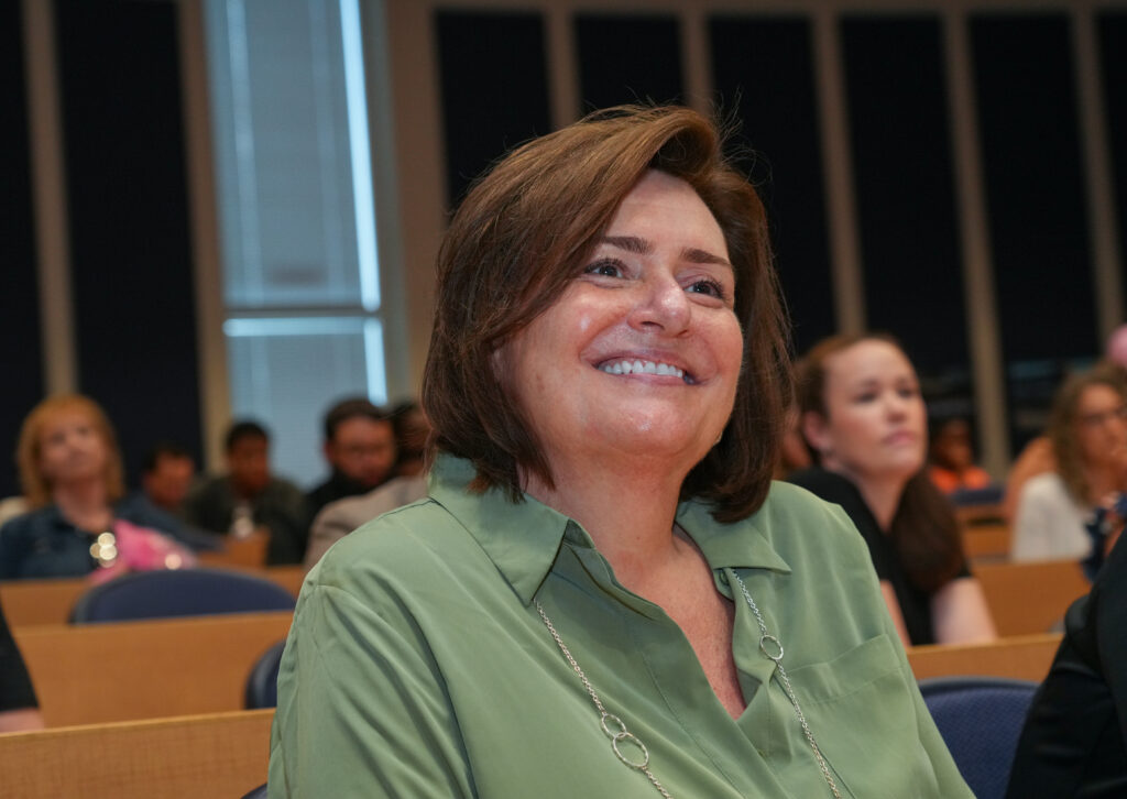 Student enrolled in online bachelor’s in respiratory therapy program sitting down and smiling at pinning celebration.