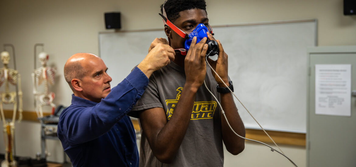 Instructor fitting a patient with a respiratory mask for therapy