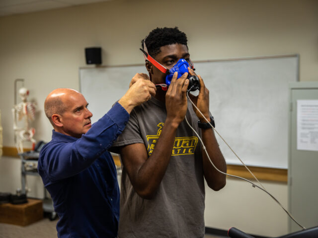 Instructor fitting a patient with a respiratory mask for therapy