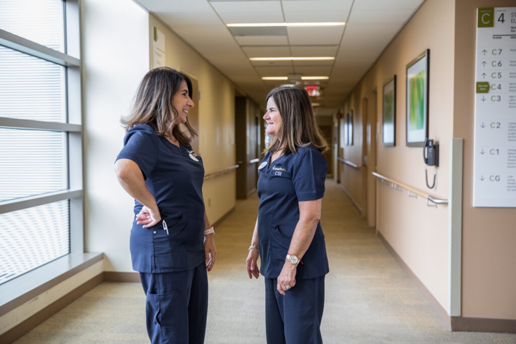 Nurse practitioners in hallway smiling at each other