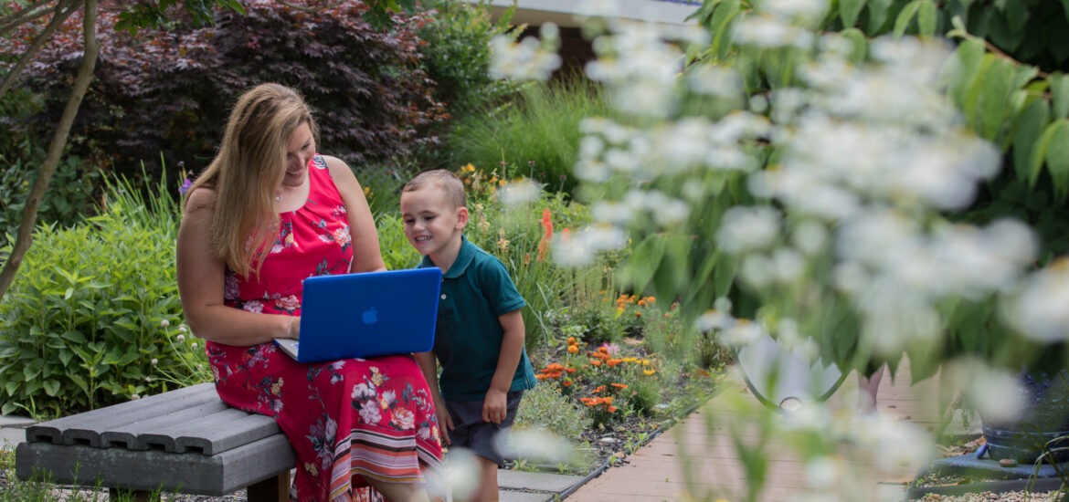 Online MBA student doing coursework on laptop with child