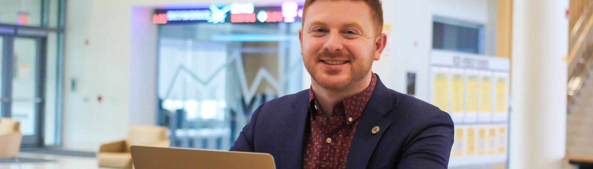 Bachelor's in business administration student smiling with laptop open.