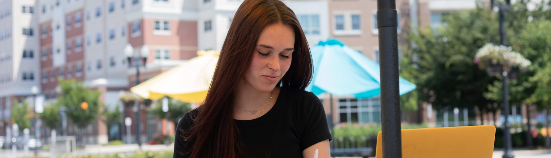 Student enrolled in Rowan’s business administration degree online, studying outdoors on her schedule.
