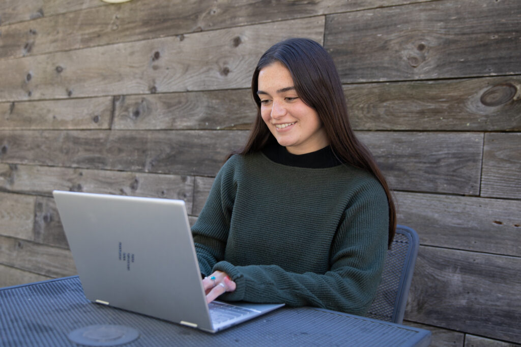 Young woman working on a laptop, exploring how to become a respiratory therapist