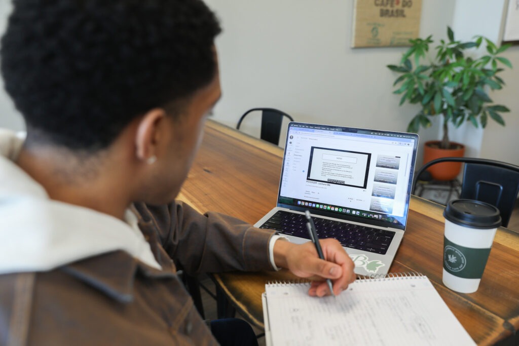 Student taking notes while studying for an online psychology degree