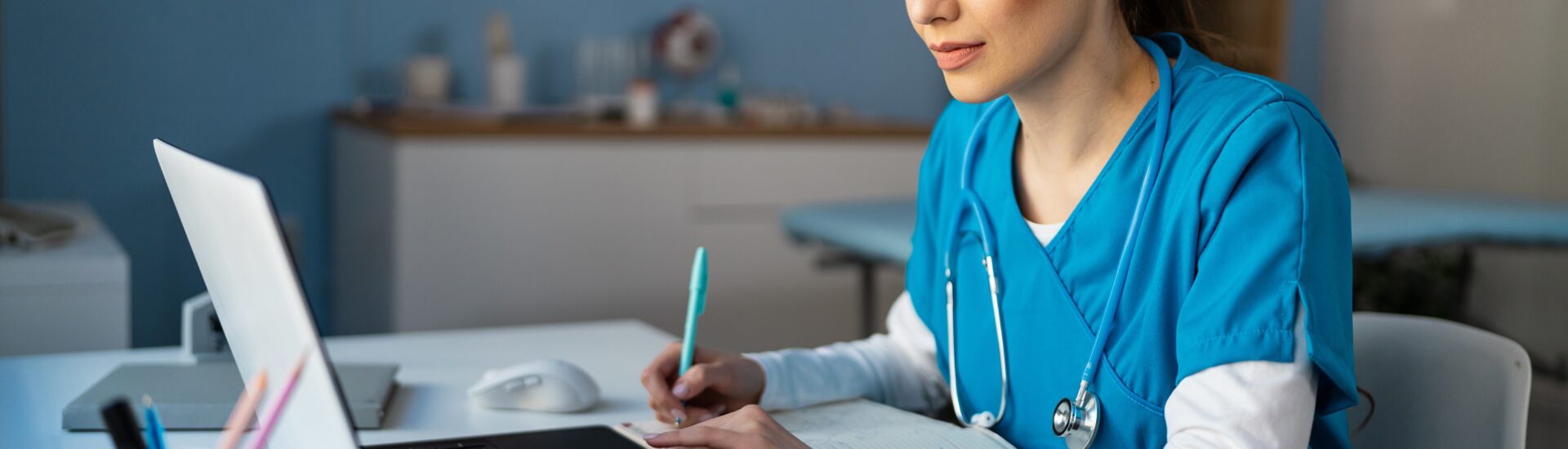 Student sitting at a table in scrubs completing coursework for a bachelor’s degree in respiratory therapy.