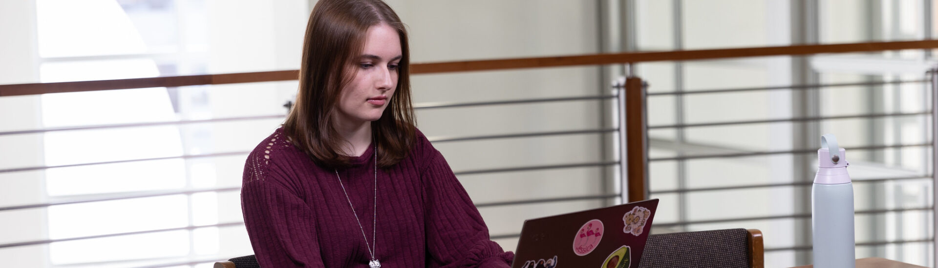 Student studying on laptop for an online finance certificate at Rowan University.