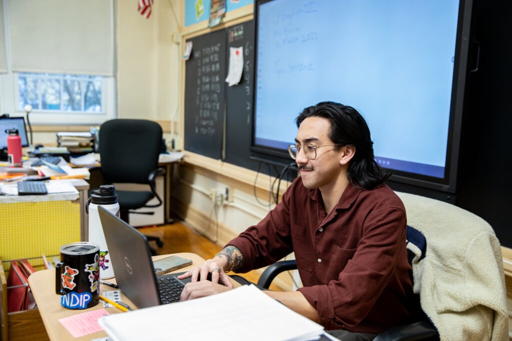 Teacher working at his desk on a laptop, completing bilingual certification online