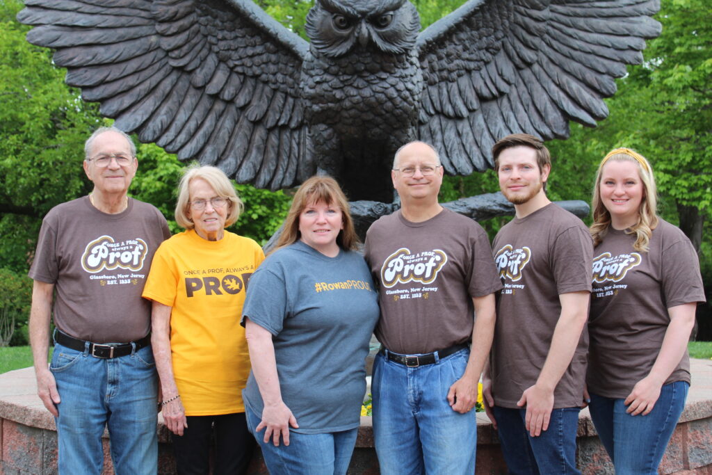 Multi-generational Rowan University alumni standing in front of the Prof statue, wearing 'Once a Prof, Always a Prof' and #RowanPROUD shirts