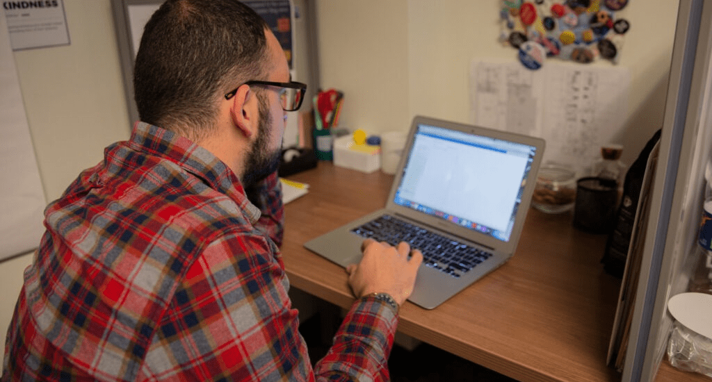 A Rowan University bilingual teacher certificate student works on his laptop in his home office.