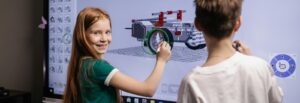 A middle school student smiles while drawing on an interactive screen, demonstrating the impact of educational technology on student learning.