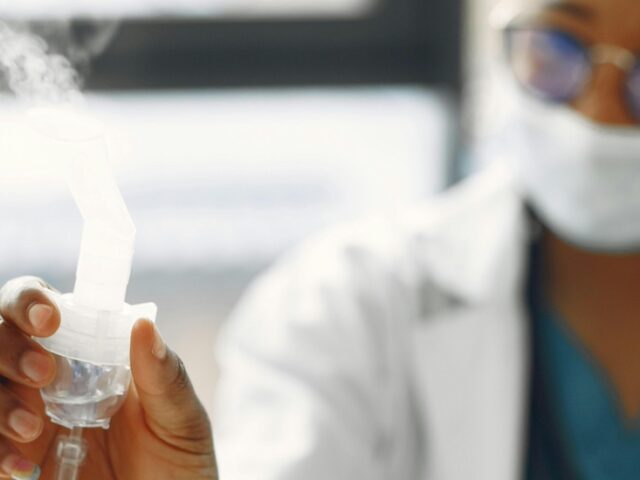 A respiratory therapist holds a nebulizer.
