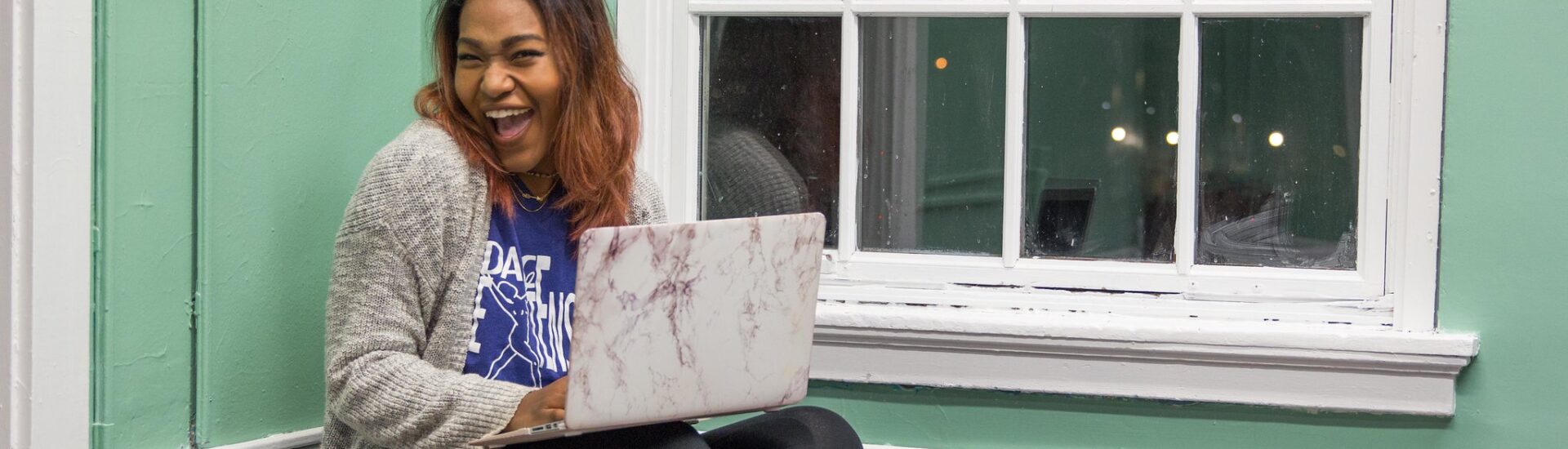 Woman studying comfortably at home with a laptop and notebook, highlighting the convenience of online graduate programs.