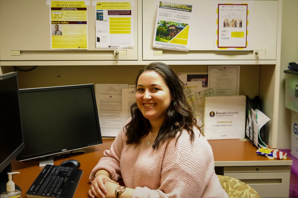 Smiling Rowan University student at a computer, pursuing a master's in educational technology online