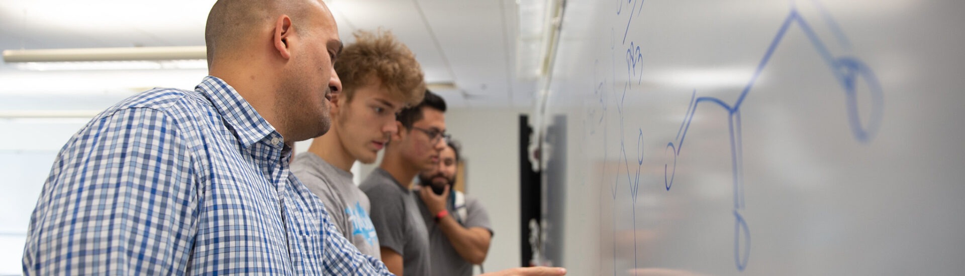 Educator guiding students through a lesson at the whiteboard, showing real-world applications of teacher leadership