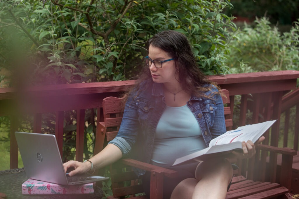 Woman earning her online master's in educational technology while studying outside on her laptop