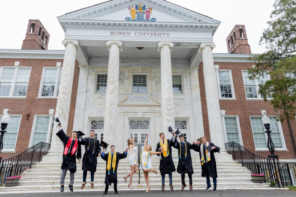 Rowan University graduates in caps and gowns celebrating in front of Bunce Hall, representing the success of both campus and online degree programs