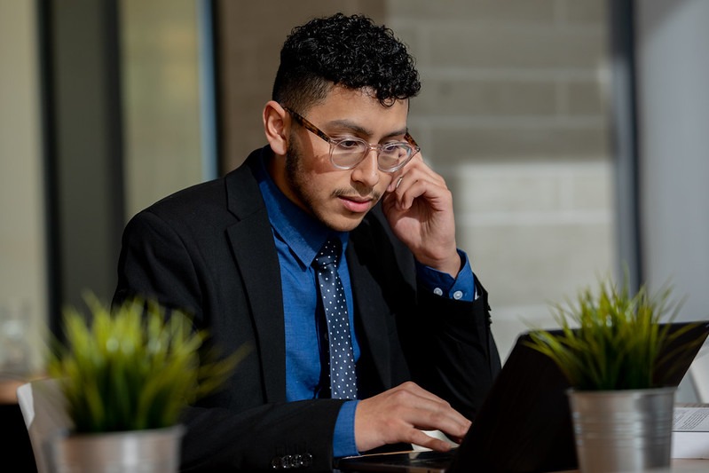 Rowan master's in cybersecurity expert works on a tablet, while holding a cell phone to his ear.