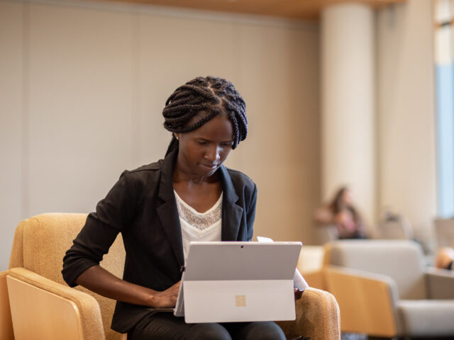 Professional woman working on a laptop in a quiet study area, representing the flexibility of an online MBA program