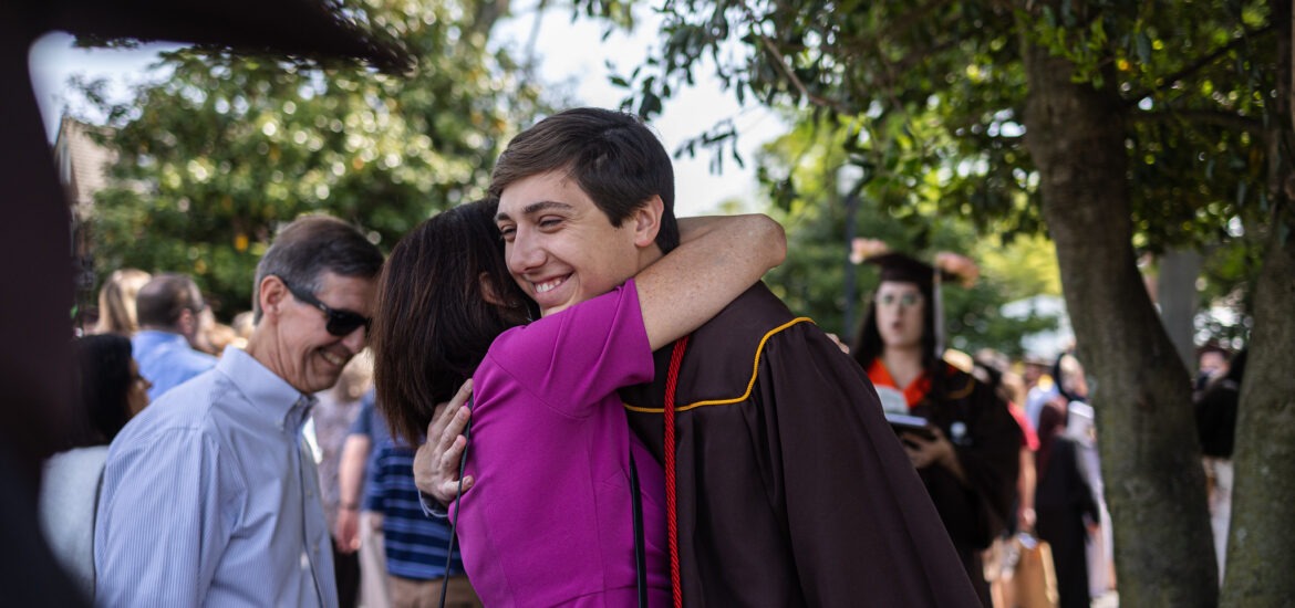 A proud parent hugs their child after graduation, celebrating a major milestone together