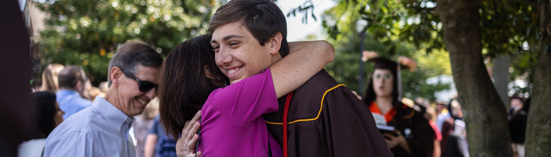 A proud parent hugs their child after graduation, celebrating a major milestone together