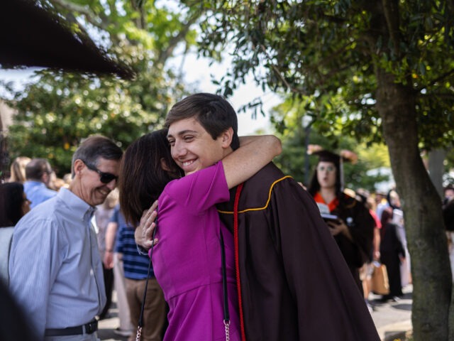 A proud parent hugs their child after graduation, celebrating a major milestone together