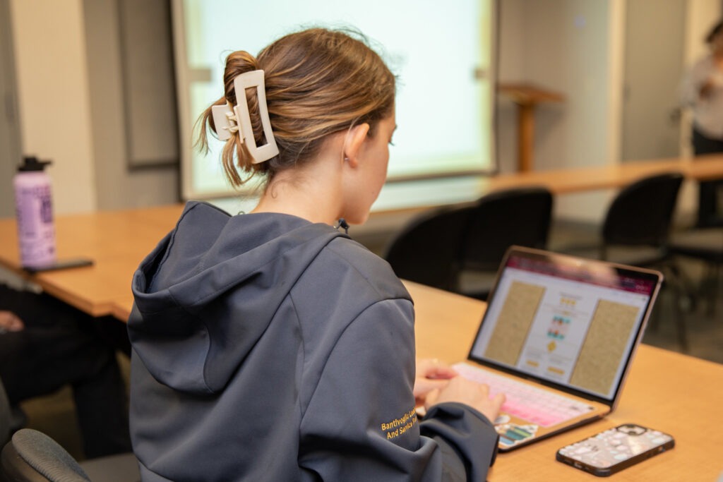 Student using a laptop in a classroom to engage with interactive coursework, highlighting the real-world relevance of online graduate programs