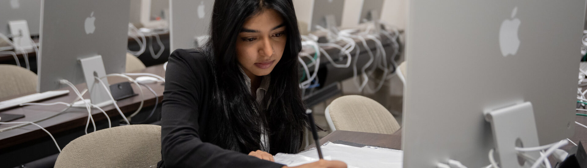 Student in computer lab taking notes while pursuing a cybersecurity masters online.