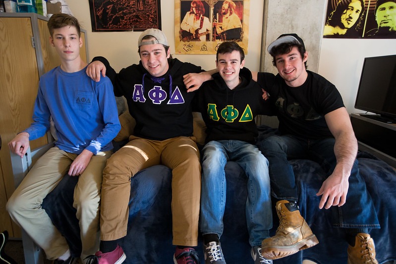 Four Alpha Phi Delta fraternity brothers at Rowan University hang out in a dorm room.
