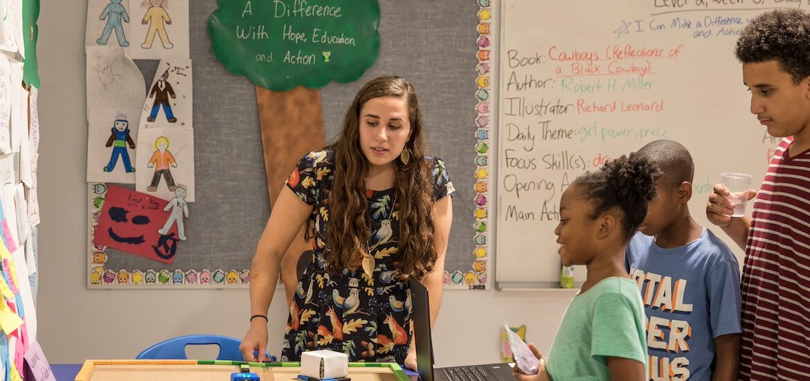 A Rowan special education master's student teaches in a classroom with students working at a table with her.