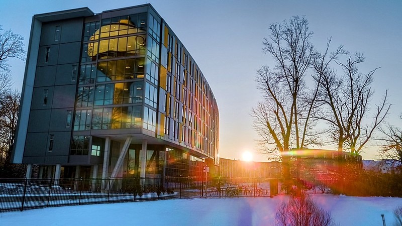 Sunrise hitting Holly Pointe dorm at Rowan University, catching the reflection of the water tower in the windows