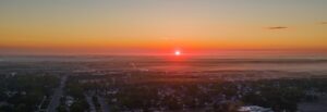 A drone photo overlooking the entirety of Rowan University's campus during a sunrise while it's still mostly dark.