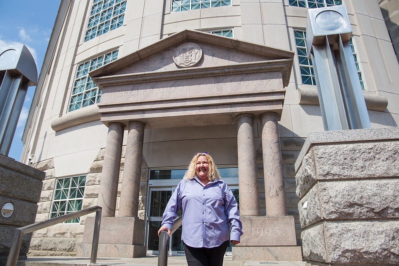 Criminal justice graduate stands outside her workplace in a courthouse.