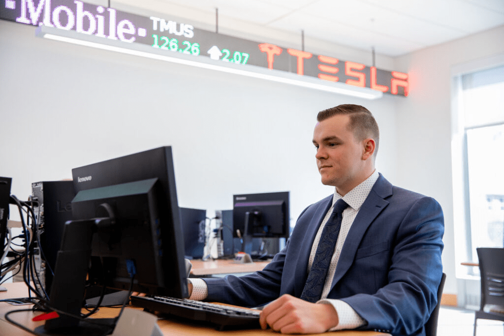 Young professional in a suit working at a computer in a business lab, representing career advancement opportunities with an online MBA