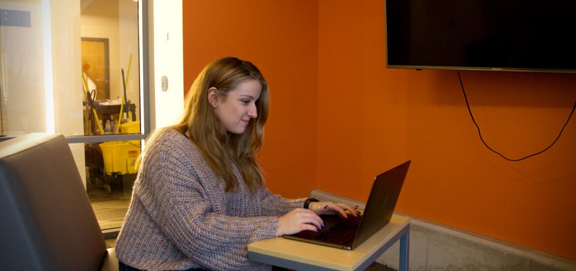 Student studies independently on a laptop in a quiet lounge, representing the flexibility of a liberal studies online program