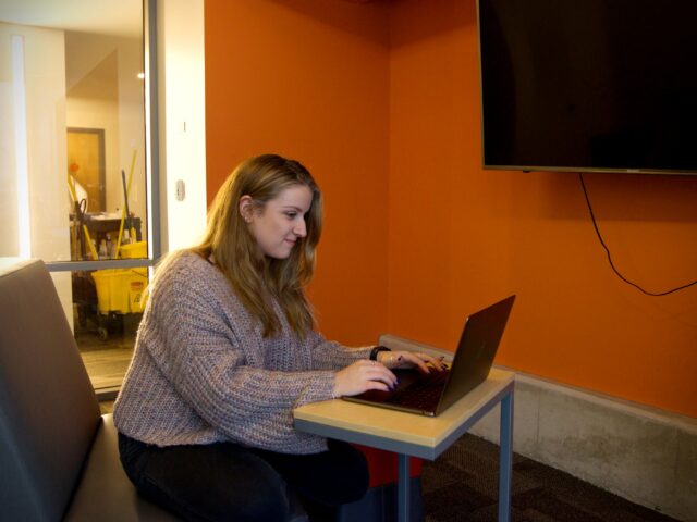 Student studies independently on a laptop in a quiet lounge, representing the flexibility of a liberal studies online program