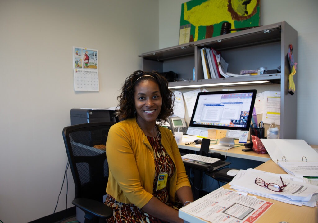Smiling educator working at desk with computer, illustrating quality instructors in EdTech programs