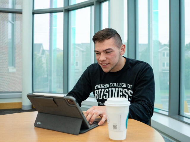 Student works on a tablet while studying in an online data analytics program