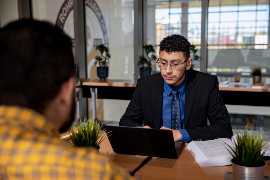 Student in professional attire works on a laptop during a one-on-one meeting, illustrating a career path possible with a liberal studies major