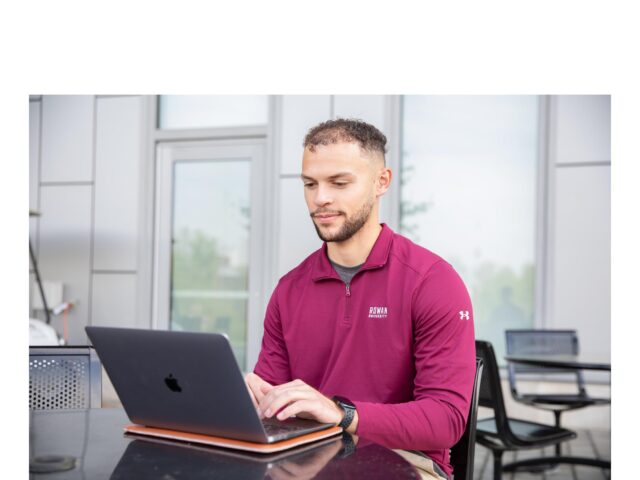 Student using laptop outdoors wearing Rowan University apparel, symbolizing how to become an EdTech professional and exploring EdTech programs
