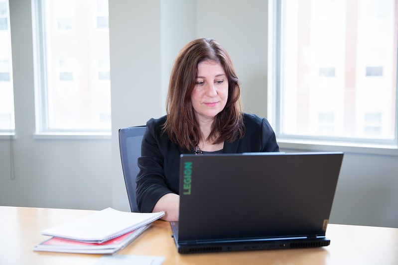 An aspiring CNO Rowan University student enrolled in the master of science of nursing, nurse executive track, works at a desk in an office with windows behind her.