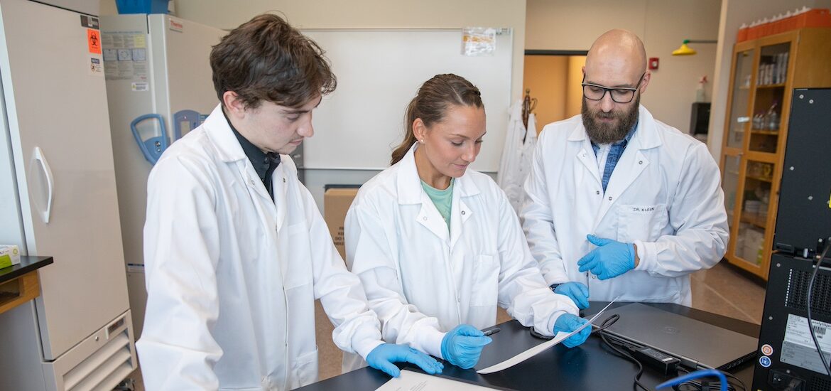 A Rowan nurse educator illustrates a point for two students in a lab.