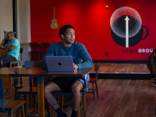 Student sitting down in coffee shop completing online coursework for bachelor of science in business administration program