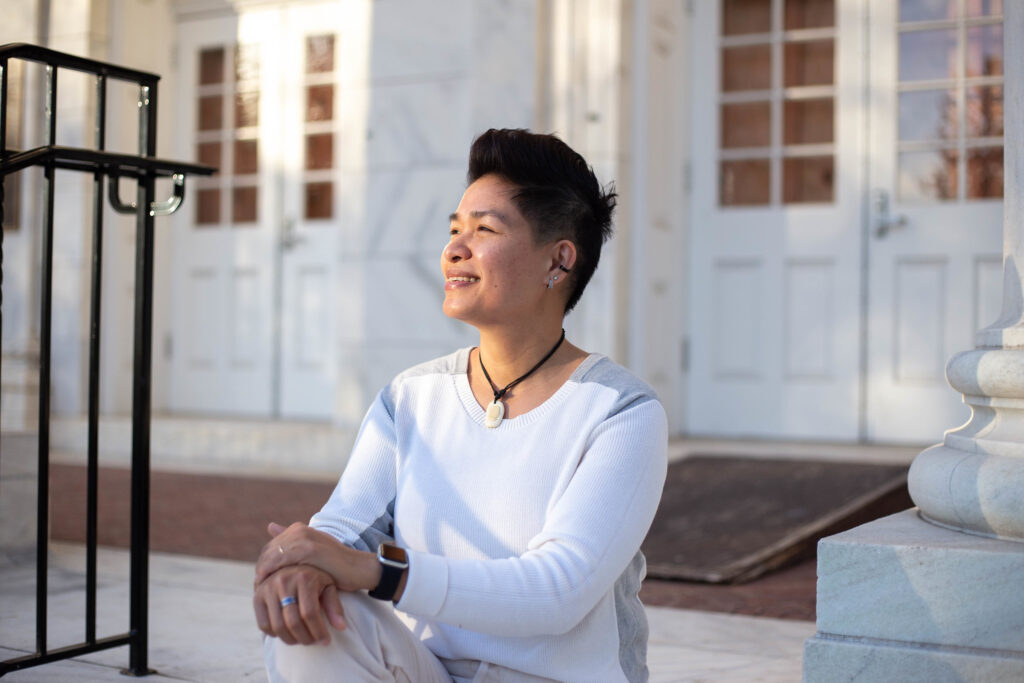 Student in bachelor of liberal studies program sitting outside on steps smiling