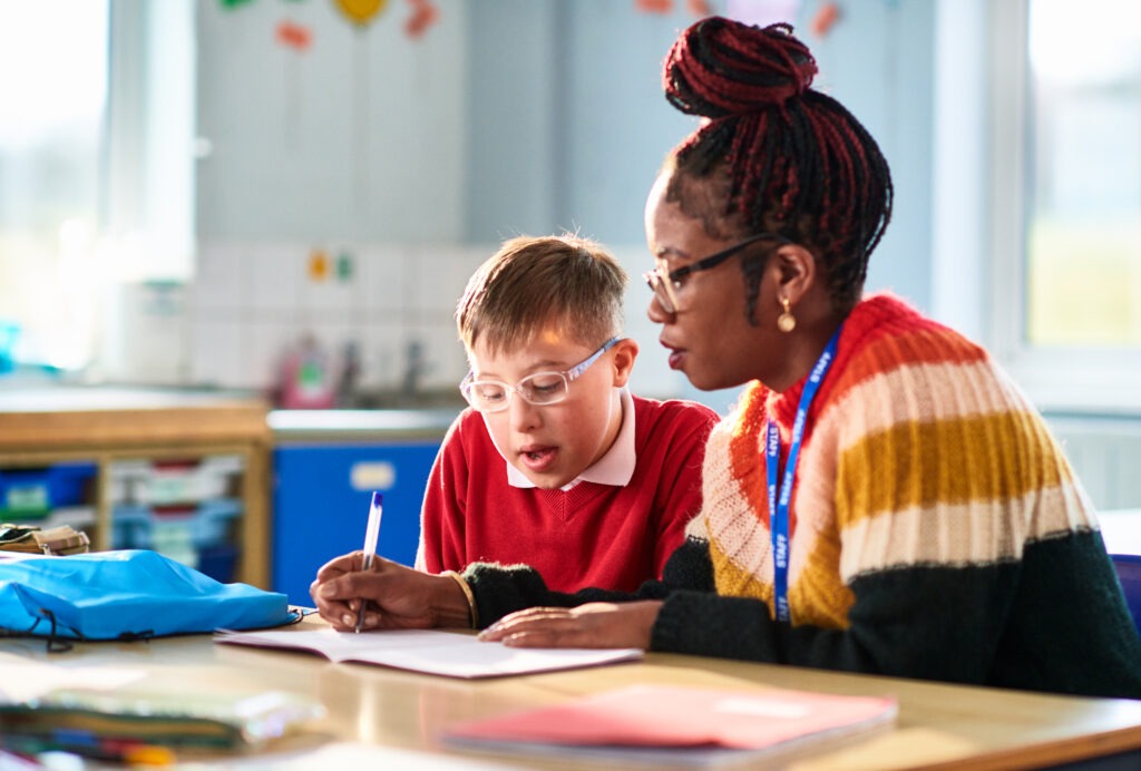 Teacher supporting a student one-on-one as part of an inclusive classroom environment in a special education master’s program
