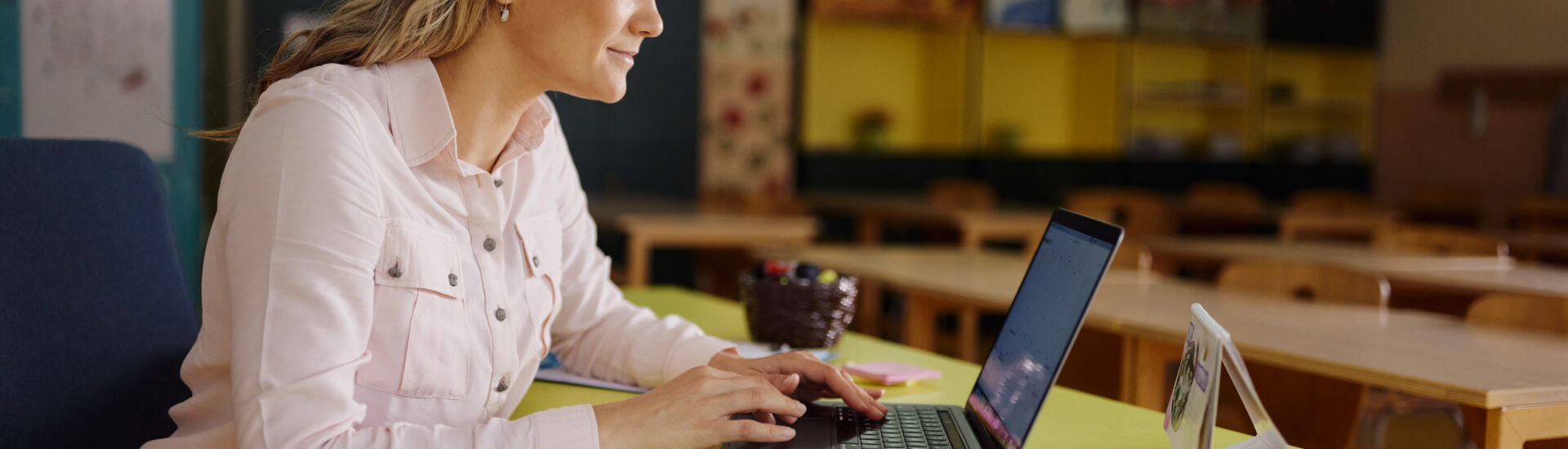 Teacher completing online coursework for her master's in educational technology while sitting in her classroom.