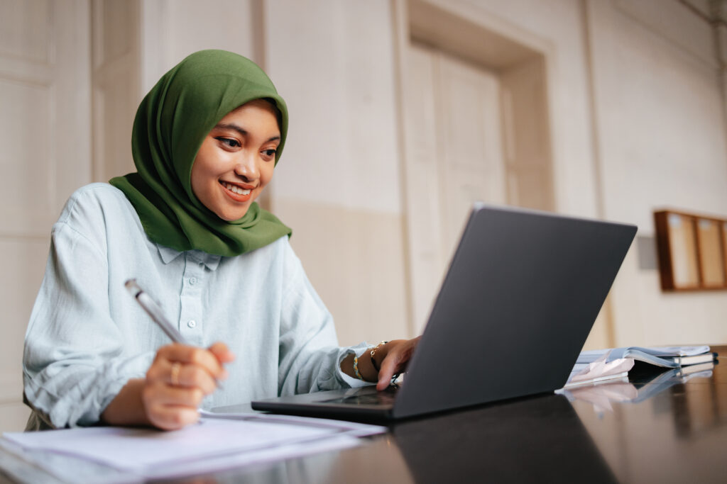 Student sitting down completing online computer information systems degree on laptop.