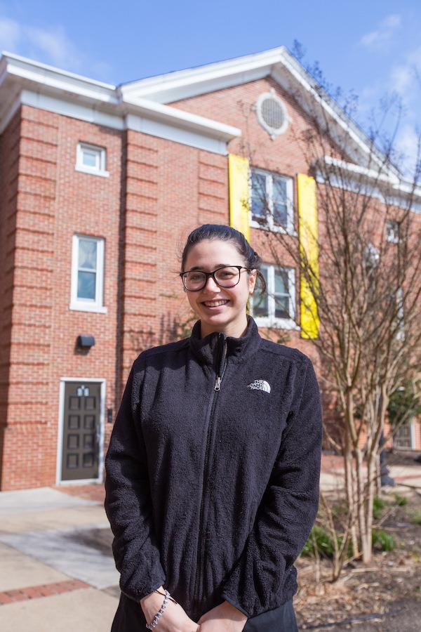 Student wears NorthFace fleece in front of Willow Hall at Rowan University.