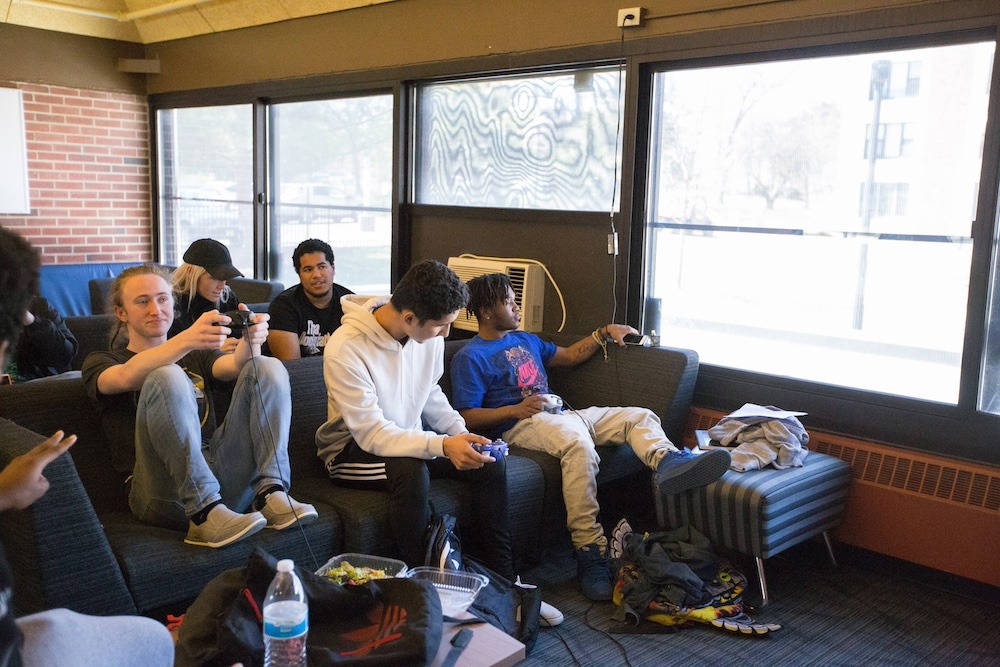 Five friends sit together in Mullica lounge, with snacks and bookbags all around them. 